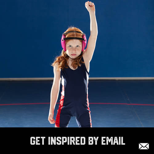 Youth sports girl wrestler standing with fist up in victory after a wrestling match in a gym