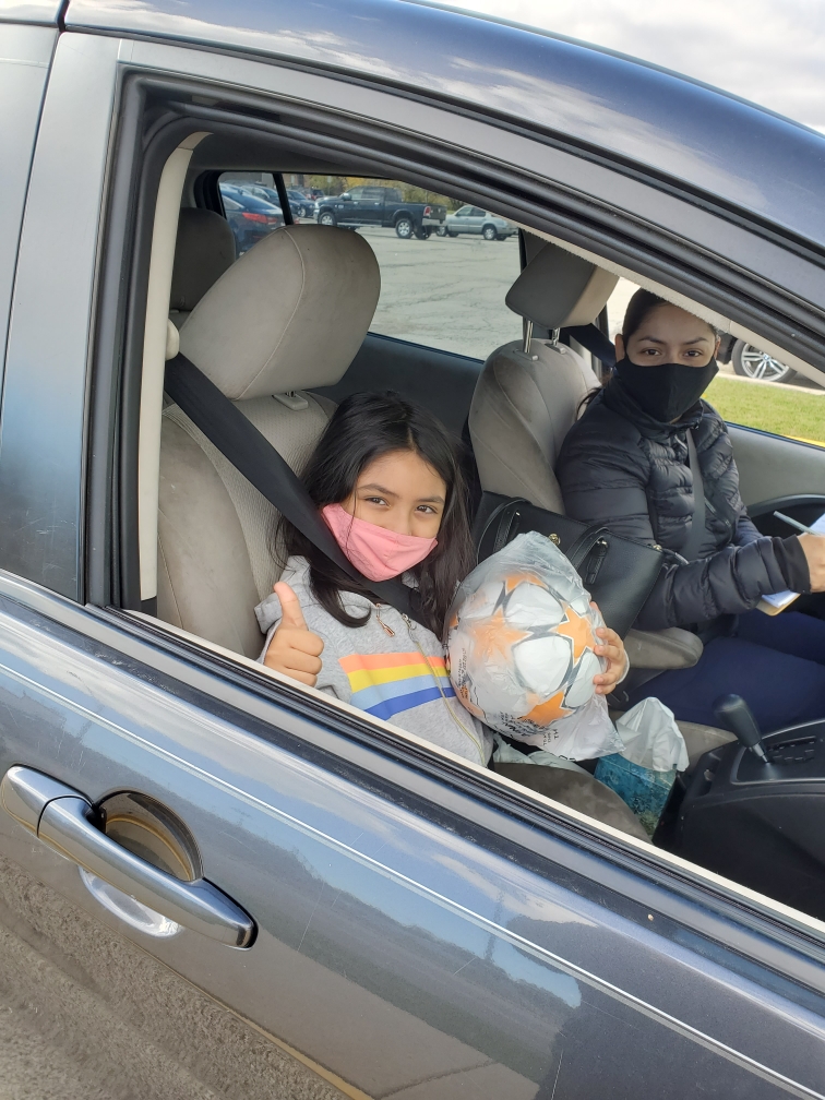 Girl athlete with mom in car with soccer ball at Foss Park District in North Chicago at All Kids Play Bounce Back sports ball giveaway