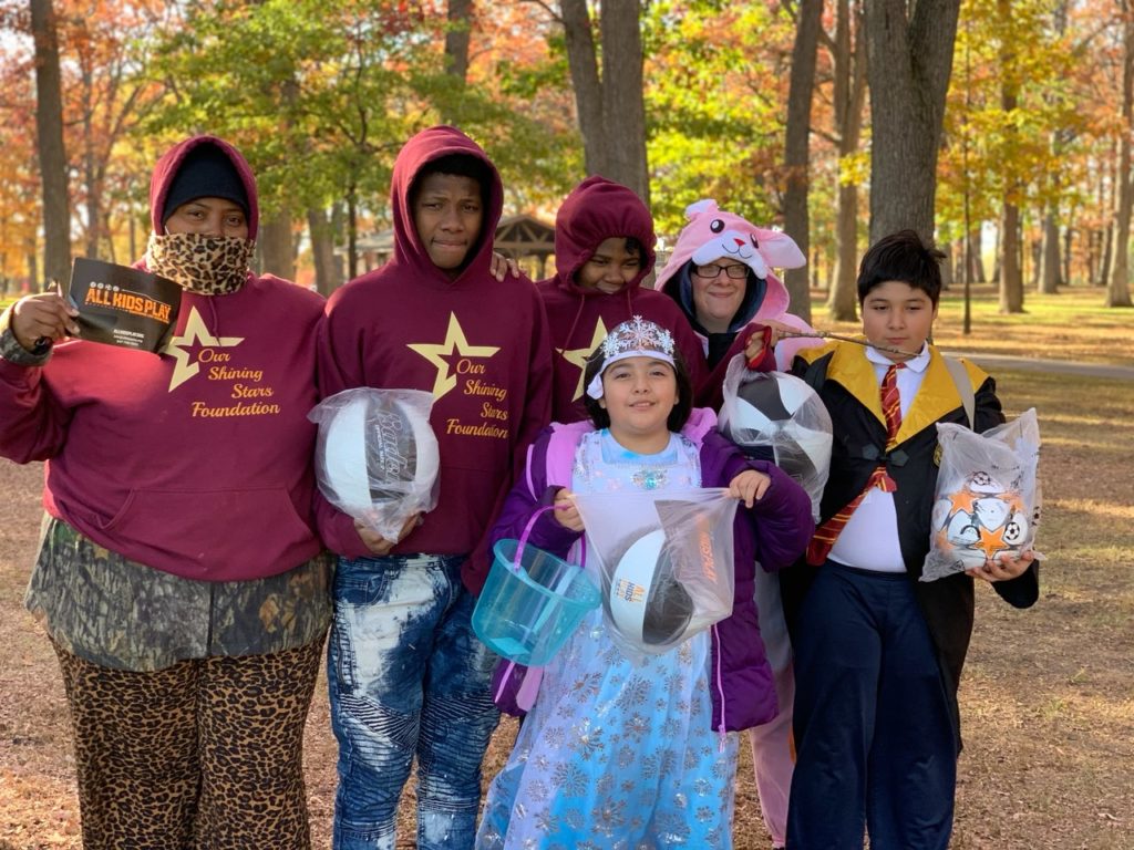 Group of youth athlete kids in Halloween costumes with soccer and basketballs at Zion Park District at All Kids Play Bounce Back sports ball giveaway