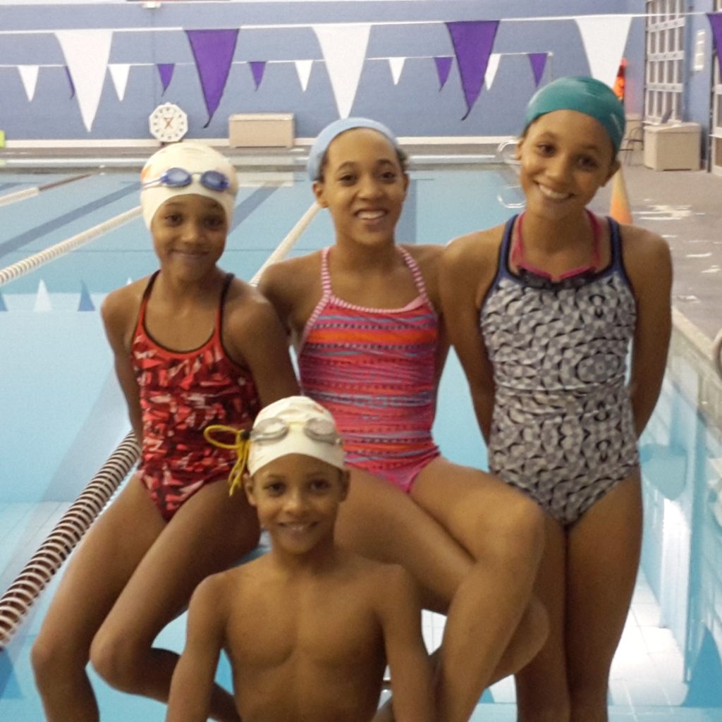 Four competitive swimming kids near pool with All Kids Play youth sports financial assistance grant