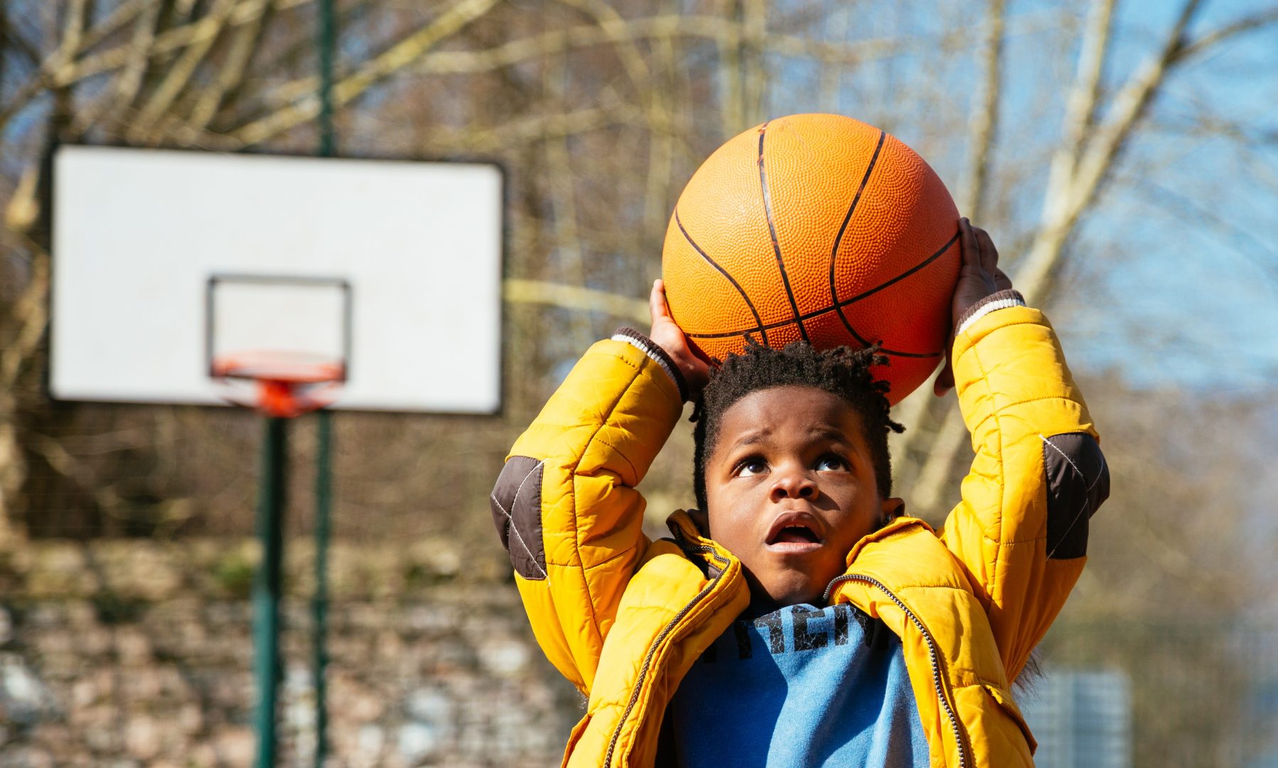 African American little boy basketball player shooting a basketball at a playground